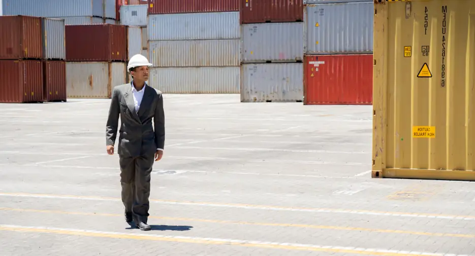 freight broker walking in yard amongst shipping containers